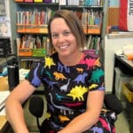 Alameda Post - Emily Piere in a classroom. She wears a colorful dinosaur dress