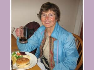 Alameda Post - Pat Gannon sits at a dinner table and smiles at the camera