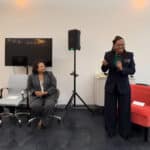 Alameda Post - one woman, Lateefah Simon, stands and speaks into a microphone while another woman looks on