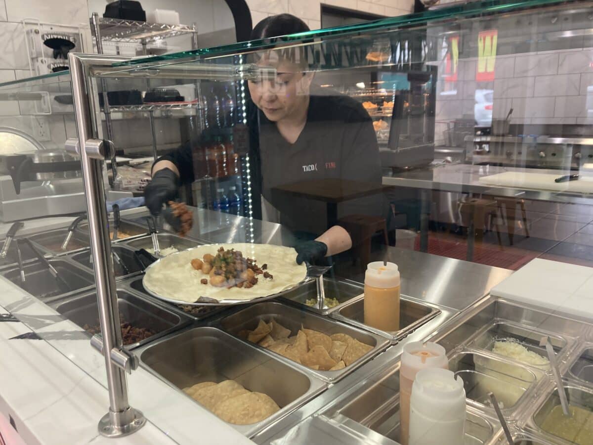 Alameda Post - behind the counter at Taco Fino, a worker prepares a burrito