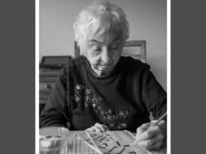 Alameda Post - an older woman, Mary Ann Bareilles Stainback Quittman, sits at a table and does a crossword puzzle