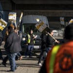 Alameda Post - amazon workers at a warehouse carry signs that say "Tannc Amazon ULP Strike" and "Amazon is Unfair Injusto"