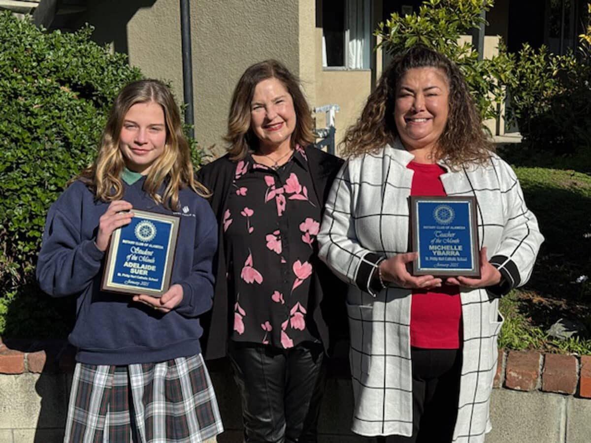 Alameda Post - a student and teacher stand holding plaques, and another woman stands in between them, the principal of St. Philip Neri Catholic School