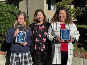 Alameda Post - a student and teacher stand holding plaques, and another woman stands in between them