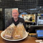 Alameda Post -John Thiel stands behind the counter of Pizzeria Pappo and smiles