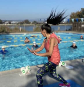 Alameda Post - a woman standing on the edge of a pool teaching water exercise
