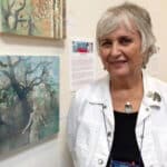Alameda Post - Bonnie Randall Boller stands next to paintings on a gallery wall