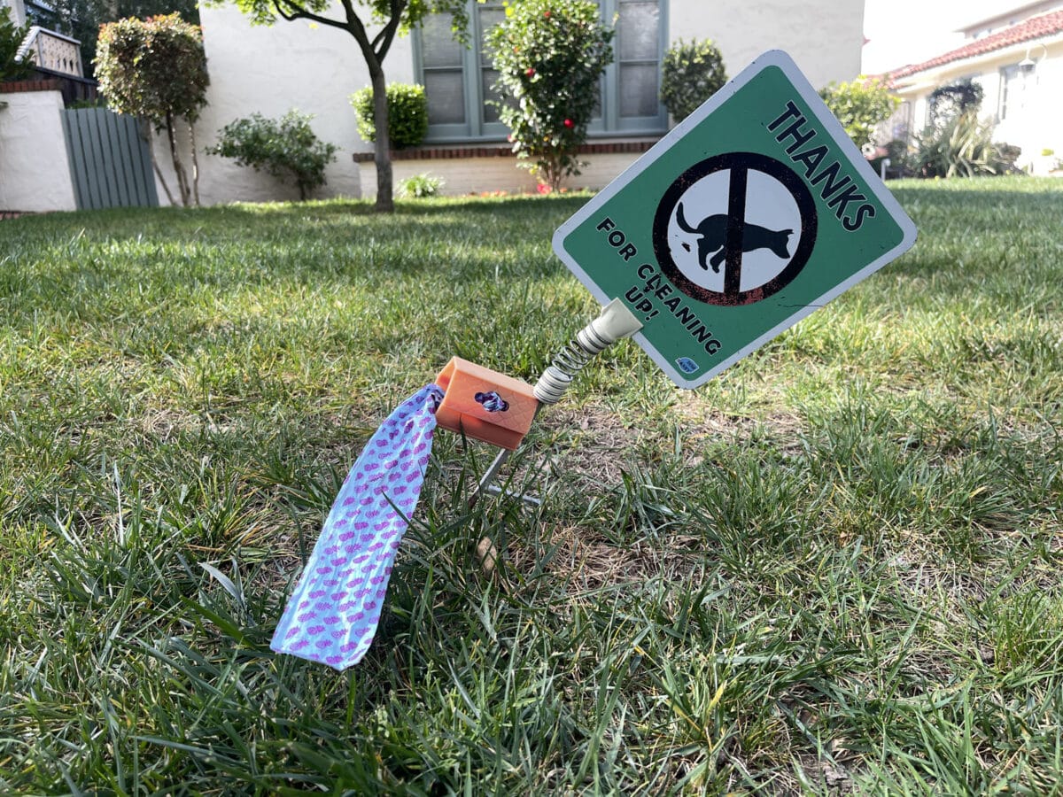 Alameda Post - a sign on someone's yard encouraging dog owners to pick up after their dogs, and a roll of poop bags