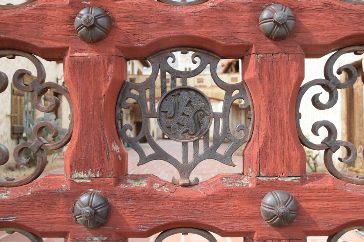 Alameda Post - a close up photo of a delicate metal piece in an elaborate fence with the letters J and S