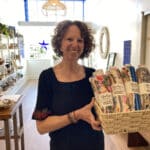 Alameda Post - a woman stands and smiles while holding merchandise in Replenish Marketplace