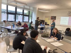 Alameda Post - an AUSD classroom with teachers or other adults sitting and working at large group desks