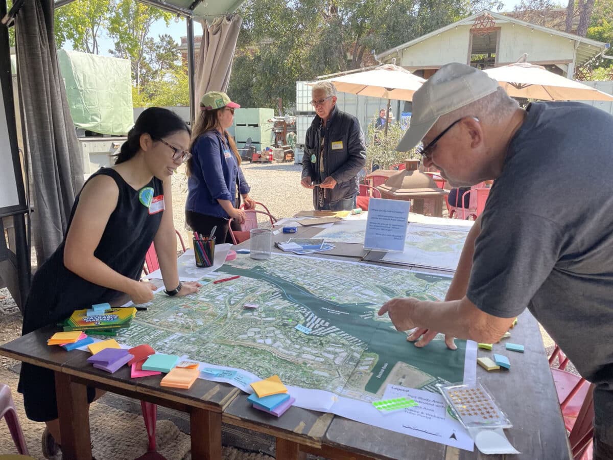 Alameda Post - a man and woman stand over a table with a large map of the coastline and piles of sticky notes