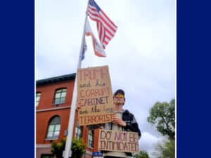 Alameda Post - a man stands in front of Alameda City Hall with signs that say "Trump and his corrupt (Nazi) Cabinet are the true terrorists. Do not be intimidated."