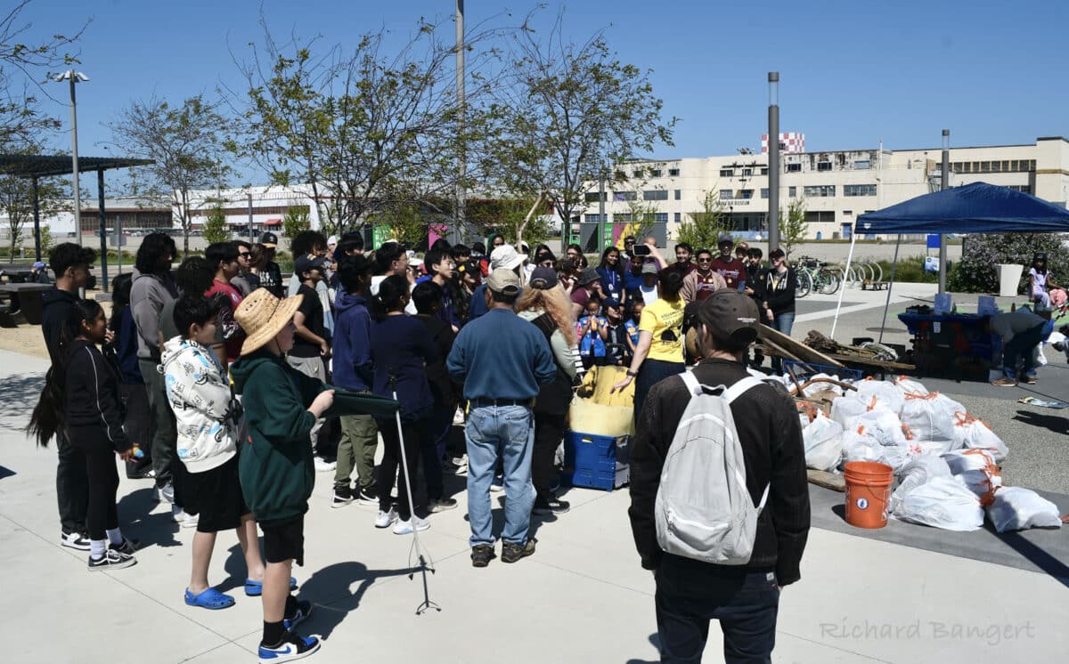 Alameda Post - a large group of volunteers gather around trash bags they collected