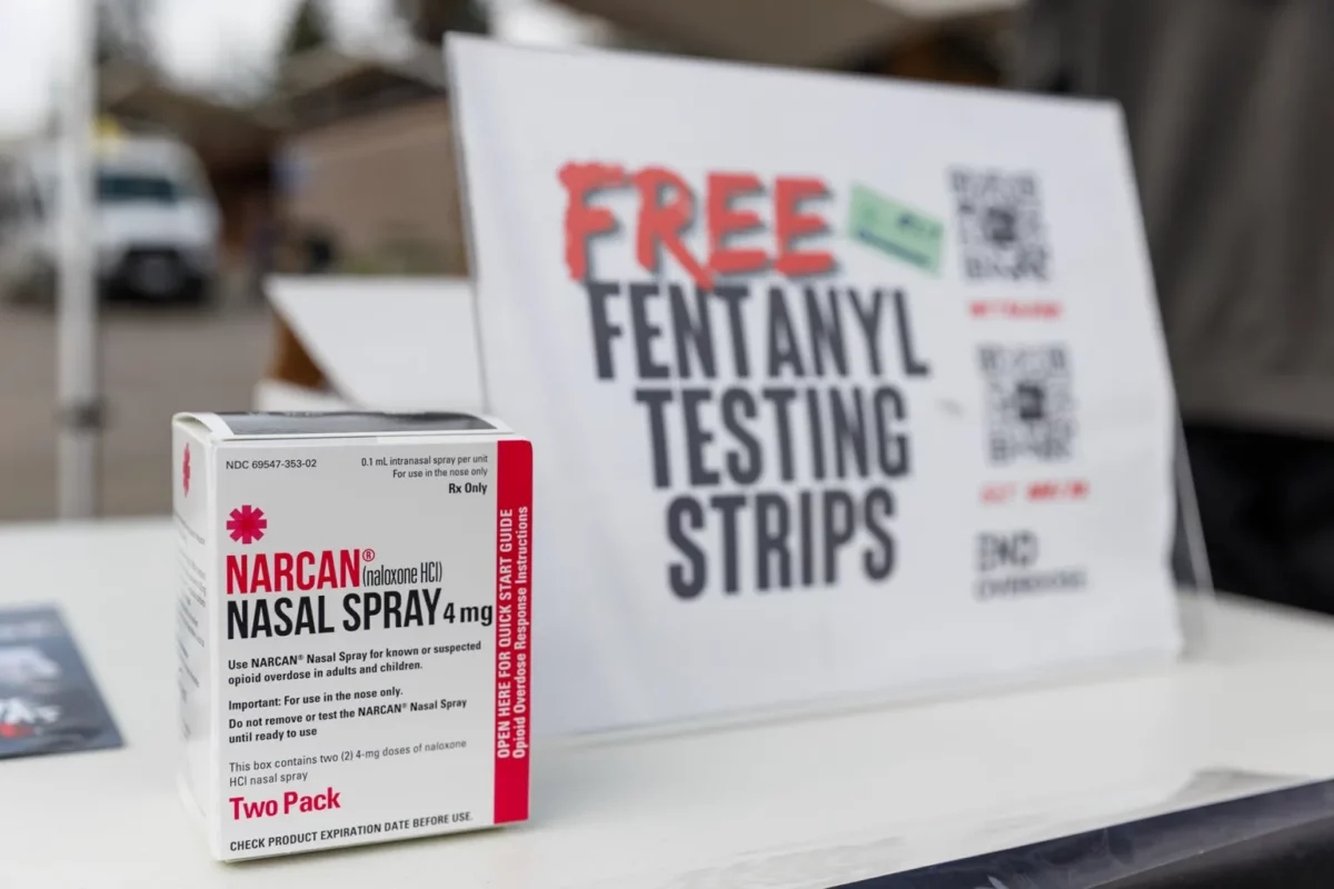 Alameda Post - a bo of Narcan, an overdose medication, next to a sign that says Free Fentanyl Testing Strips