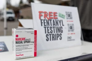 Alameda Post - a bo of Narcan next to a sign that says Free Fentanyl Testing Strips