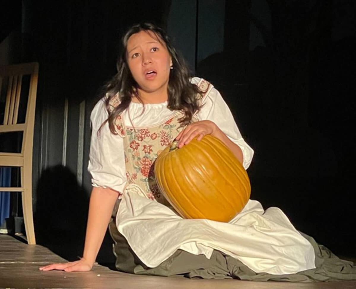 Alameda Post - the actress playing Cinderella sits on the ground holding a pumpkin