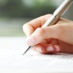 Alameda Post - a woman's hand holds a pen and fills out a form