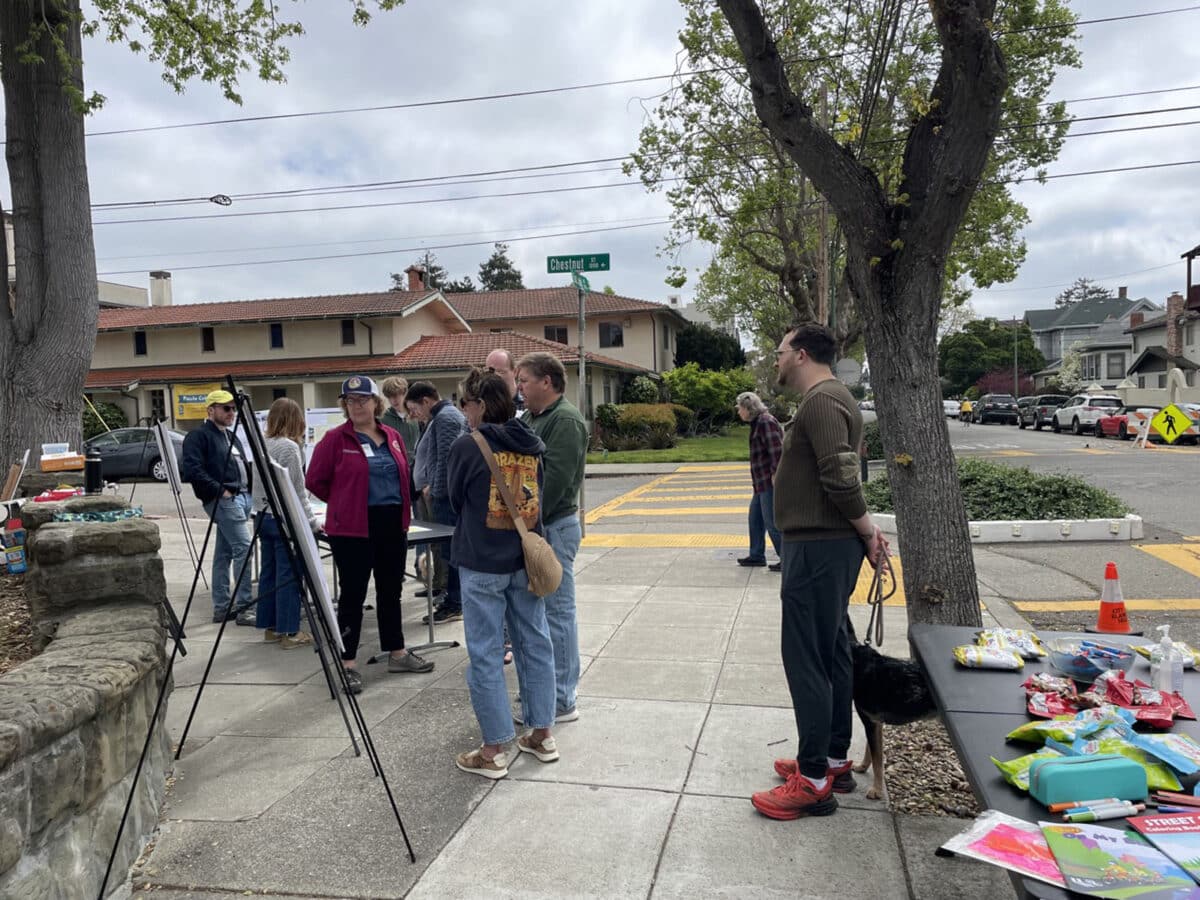 Alameda Post - neighbors stand at a large sidewalk area on a street corner and review plans on large boards