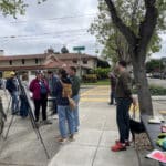 Alameda Post - neighbors stand at a large sidewalk area on a street corner and review plans for greenways