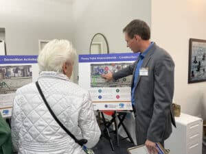 Alameda Post - a staff member points at a map of the Oakland Alameda Access Project plans and speaks to a white haired, older community member