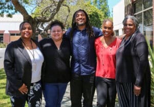 Alameda Post - five people of color who comprise the AUSD Office of Equity stand together and smile at the camera