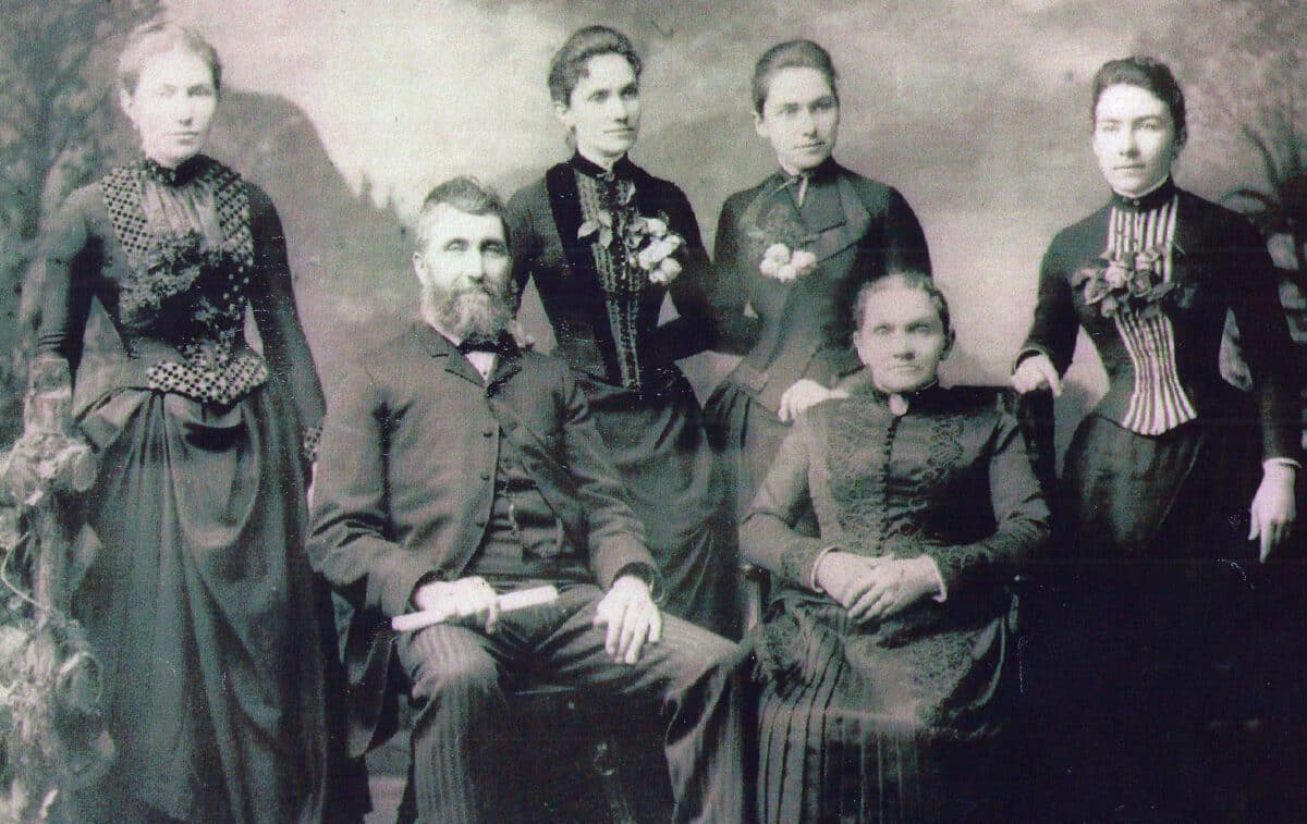 Alameda Post - a black and white formal portrait of a mother and father surrounded by their four teenage or young adult daughters