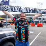Alameda Post - an Oakland Roots fan wearing a jersey holds up a scarf that says "Los Roots" in front of the Colosseum before the match versus Orange County SC