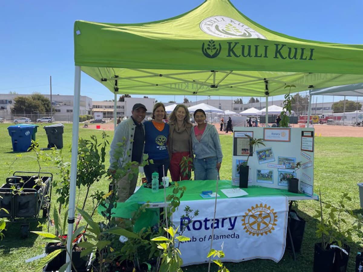 Alameda Post - a group of four people smile and pose at a Rotary Club of Alameda booth at the Spring Shindig