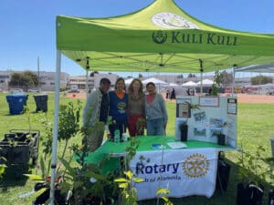 Alameda Post - a group of four people smile and pose at a Rotary Club of Alameda booth at the Spring Shindig