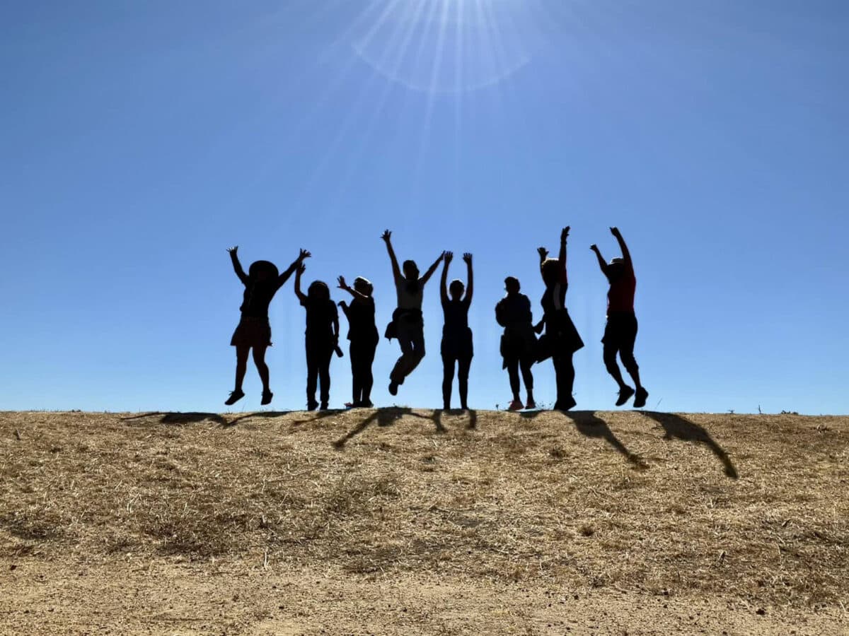 Alameda Post - eight women in the Alameda walking group jump into the air on a hill