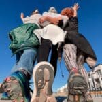 Alameda Post - a group of three women in walking shoes strike a pose. The camera is set behind them, so their shoes and backs are in frame.