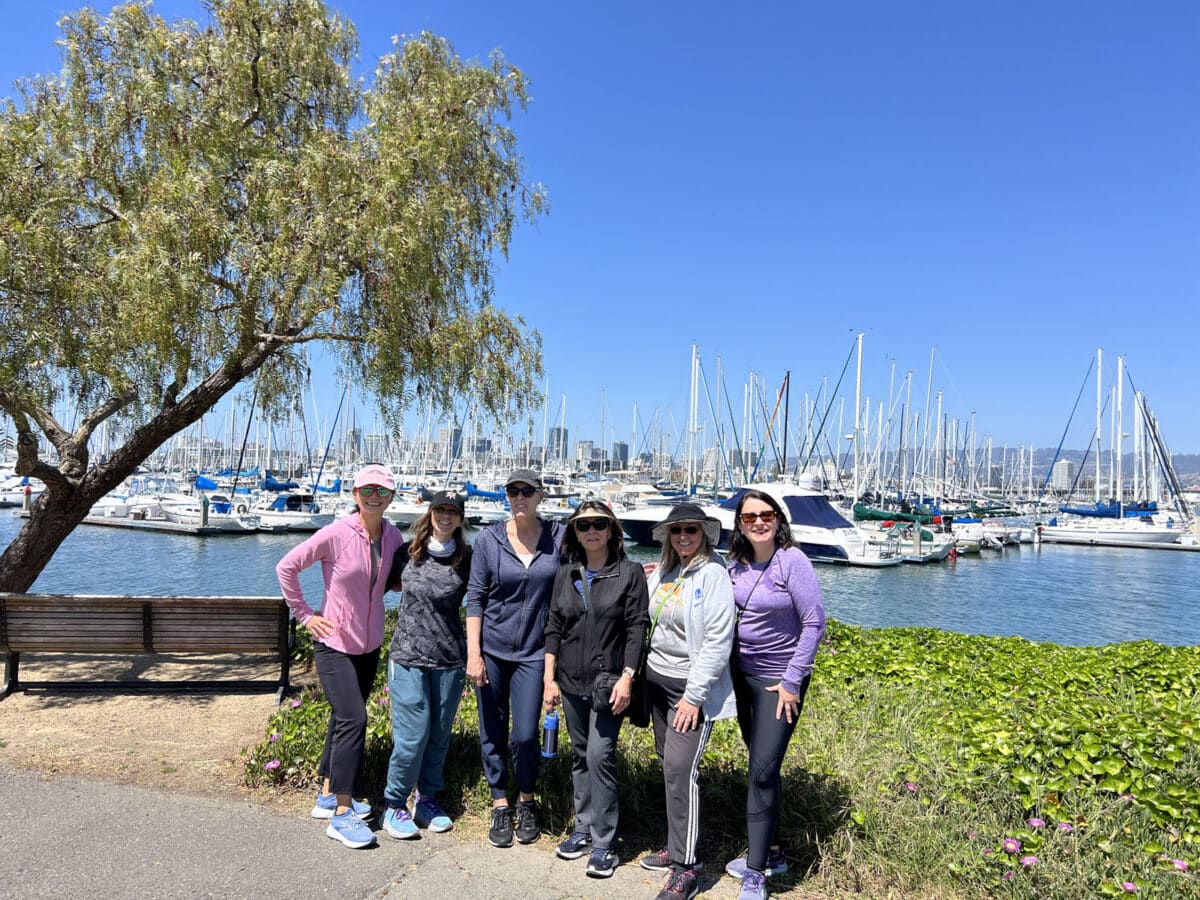 Alameda Post - six women stand by the Alameda waterfront with boats in the background