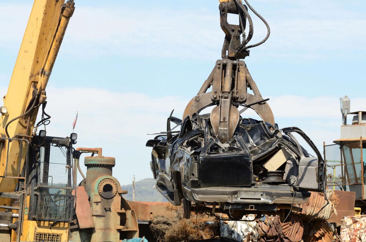 Alameda Post - a crane lifts a car, presumably at a recycling facility