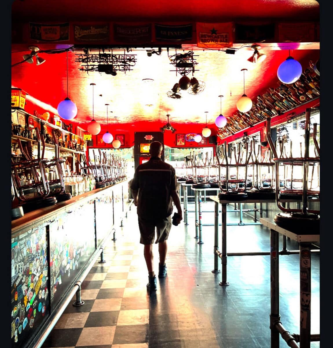 Alameda Post - Derrick Reynolds, wearing his UPS uniform, walks away from the camera in what appears to be Lucky 13 bar on Park Street