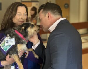 A woman holds a dog while a man pets the dog.