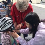 Alameda Post - adults help a young child with a helmet fitting at the Alameda Bike Festival at Paden