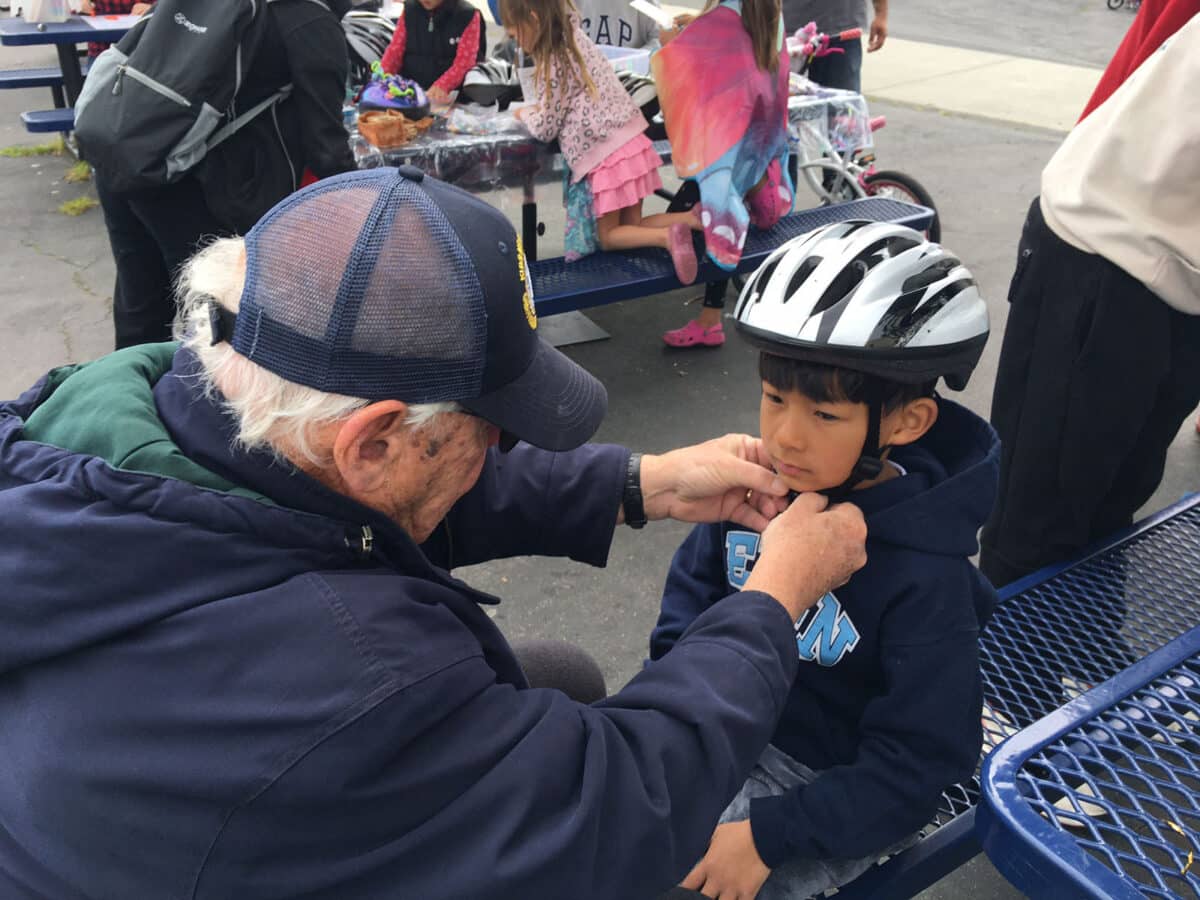 Alameda Post - a child receives a helmet fitting from an adult