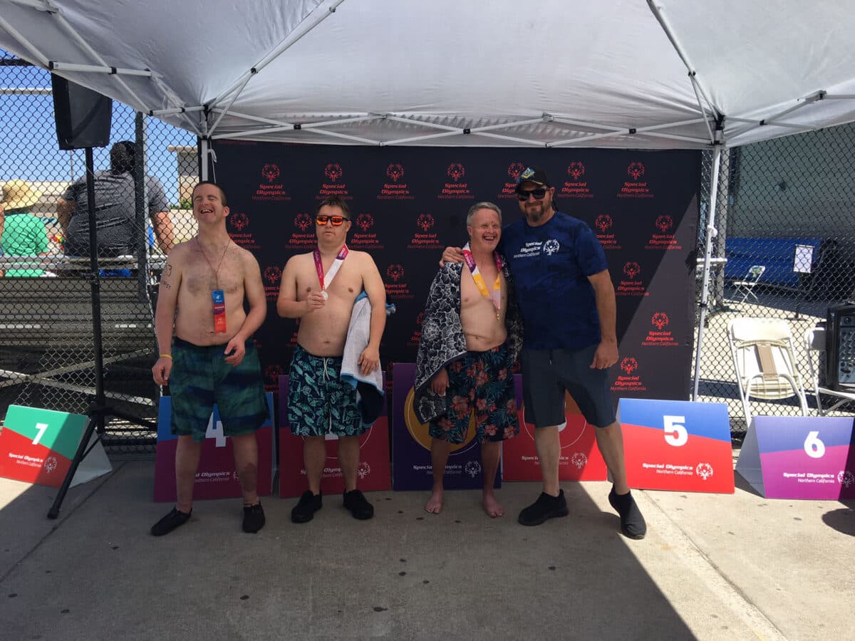 Alameda Post - three swimmers stand with one coach or mentor