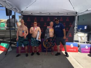 Alameda Post - three swimmers stand with one coach or mentor