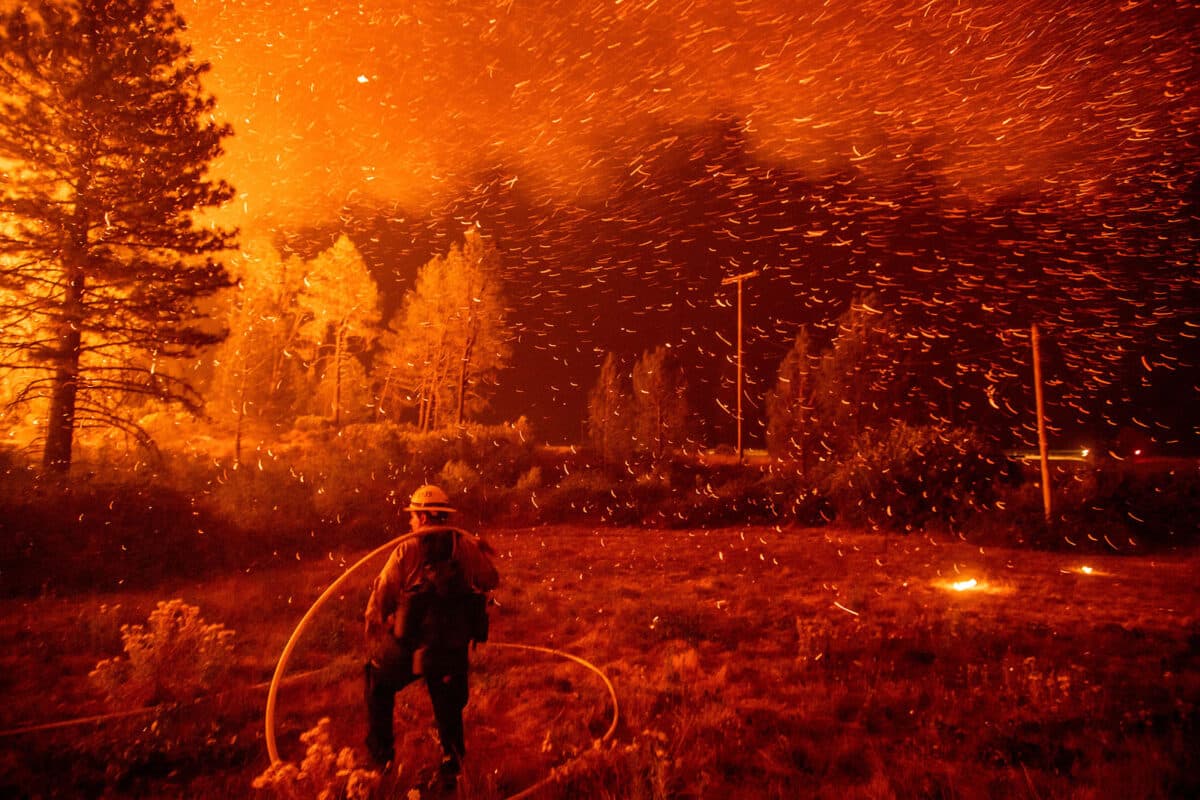 Alameda Post - A firefighter fights a blaze in an eery red photo of a forest fire