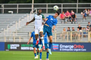 Alameda Post - an Oakland Roots and North Carolina FC jump into the air trying to head the ball