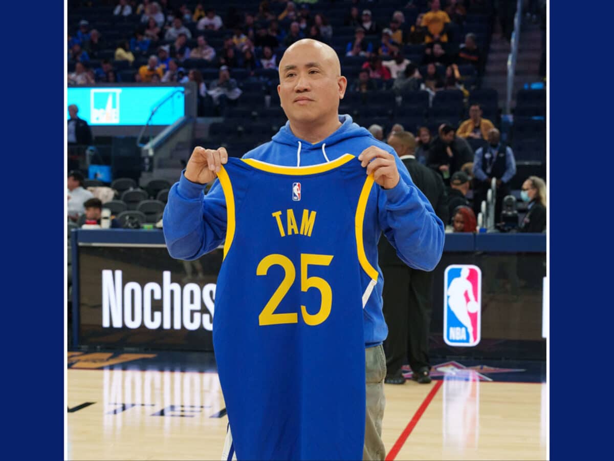 Alameda Post - Chris Tam holds up a Jersey that says "Tam" with the number 25