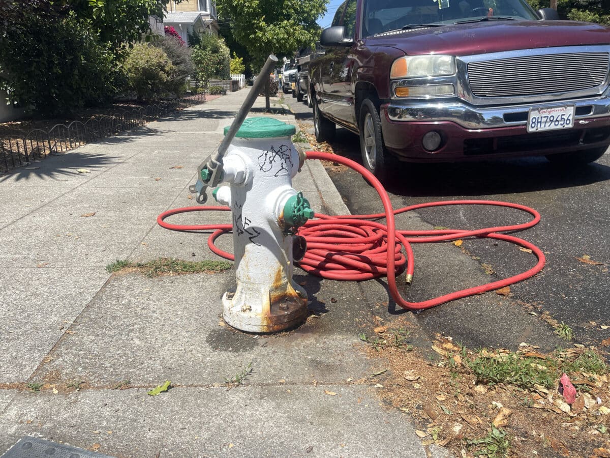 Alameda Post - a fire hydrant with a crank and a hose attached