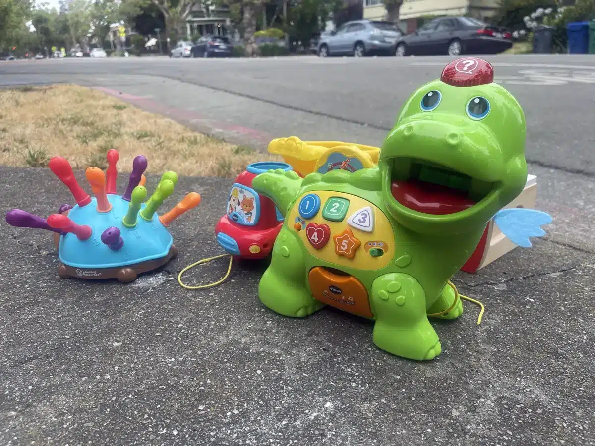 Alameda Post - Bear's-Eye View of Alameda for June 29, 2025. A brightly colored plastic dinosaur toy