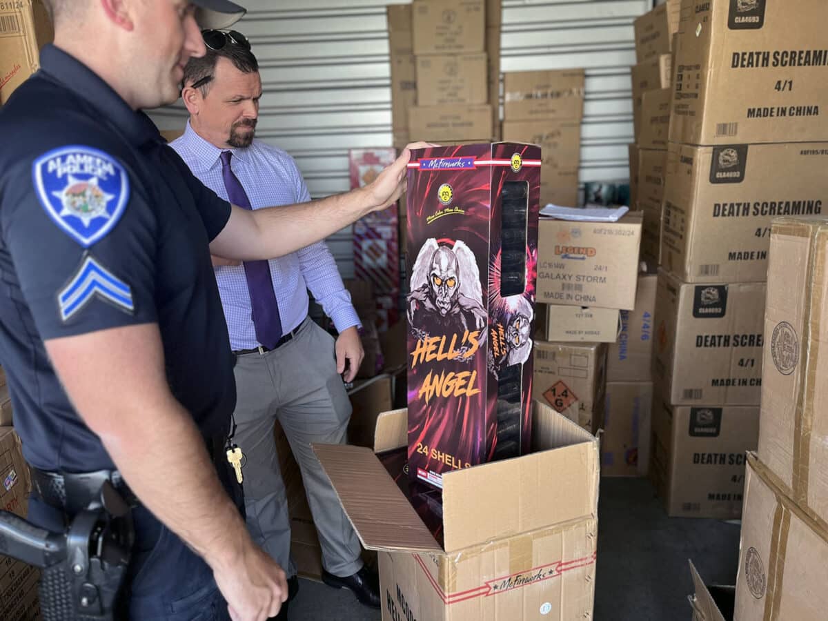 Alameda Post - An Alameda Police officer and another man inspect illegal fireworks seized from a storage unit.