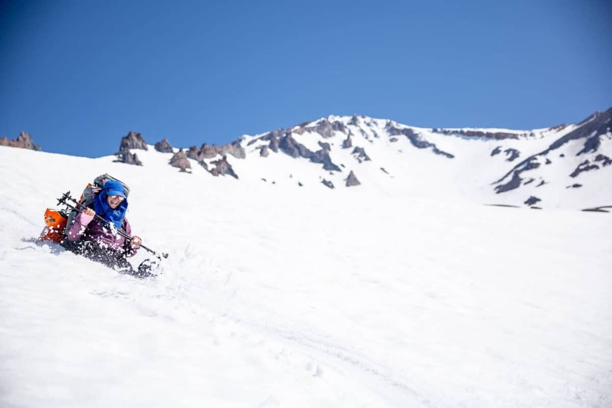Alameda Post - a hiker smiles and sits in the pure snow on Mount Shasta