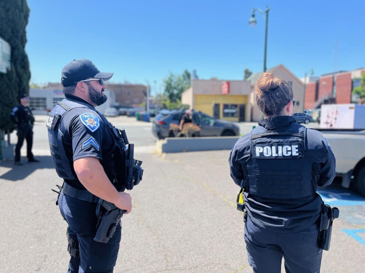 Alameda Post - two APD officers stand and look out over a parking lot