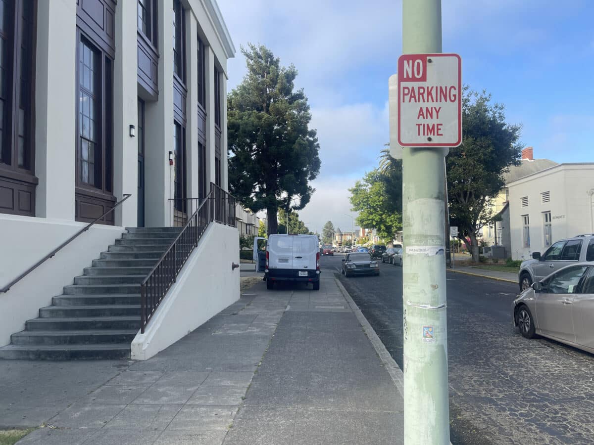 Alameda Post - a van parked up on the curb/sidwalk/concrete next to a building 