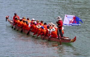 Alameda Post - the dragonflyers paddle in the water with an Alameda flag on the back of the boat